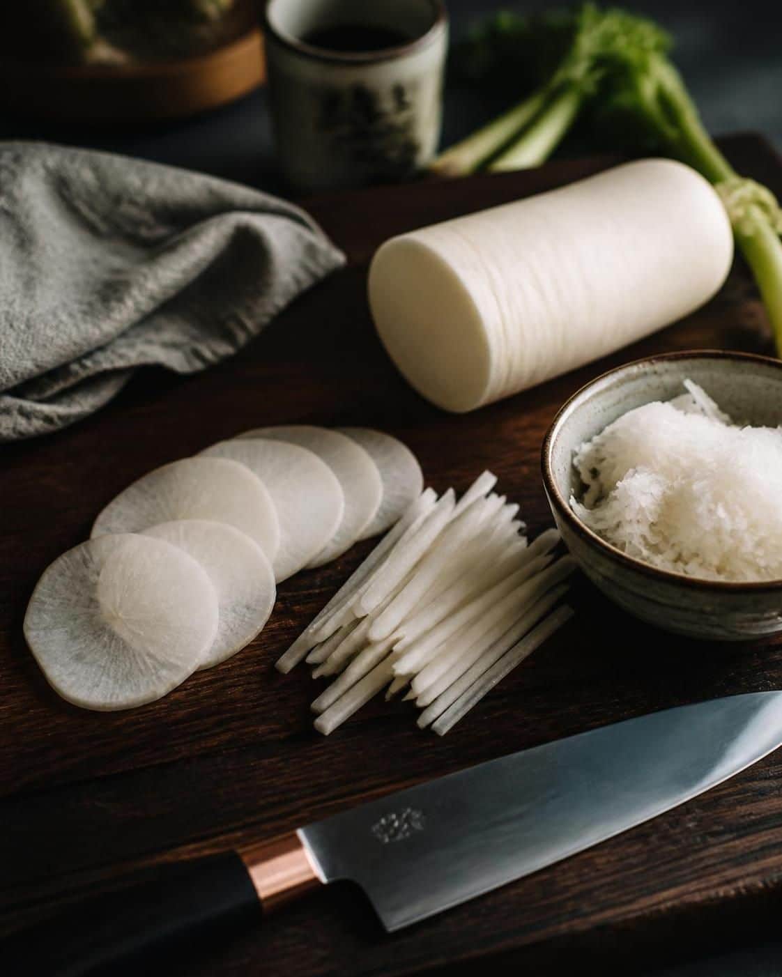 Radis blanc en rondelles, en bâtonnets et râpé sur une planche en bois avec un couteau