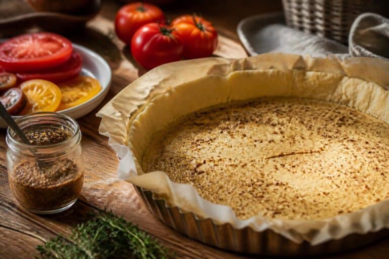 Fond de tarte cru couvert de moutarde avec des tomates coupées à côté